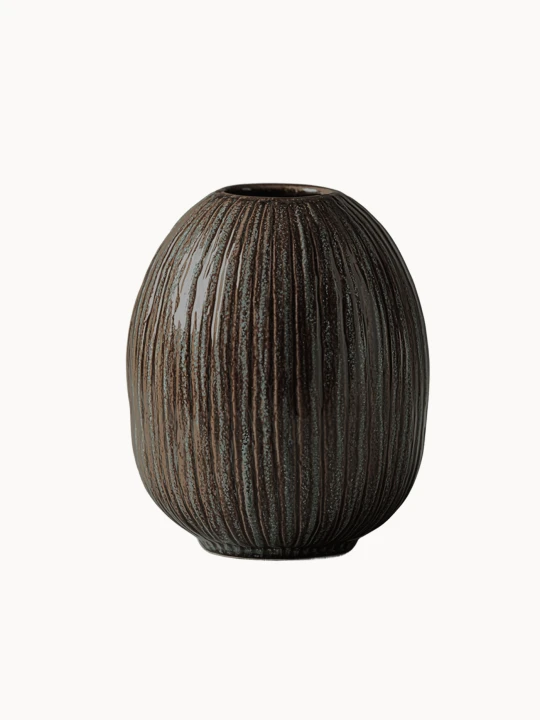 Owalny, ciemnobrązowy wazon ceramiczny o strukturalnej powierzchni pokrytej pionowymi, żłobionymi liniami z subtelnym zielonym akcentem, na białym tle.